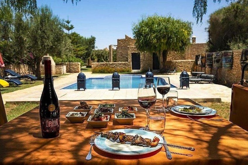 An outdoor dining table with food, wine, and a bottle of wine. 4