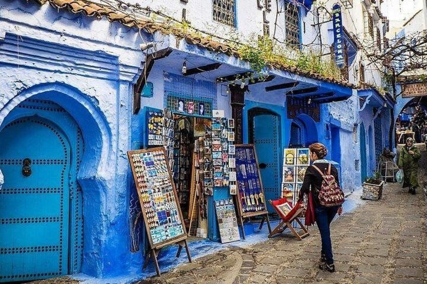 A blue-painted building with a shop displaying jewelry and postcards. 5