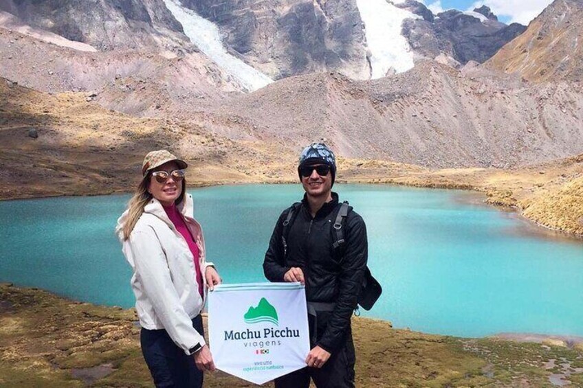 Deux personnes se tiennent près d’un lac turquoise, avec un glacier en arrière-plan. 5