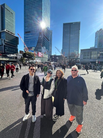 A group of people standing in a busy urban street with tall buildings and construction cranes in the background. 2