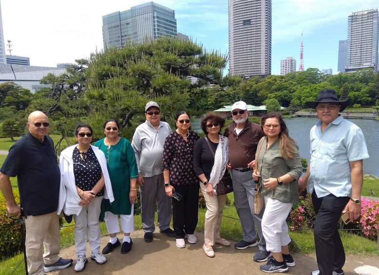 A group of people standing in a park with a lake and buildings in the background. 4