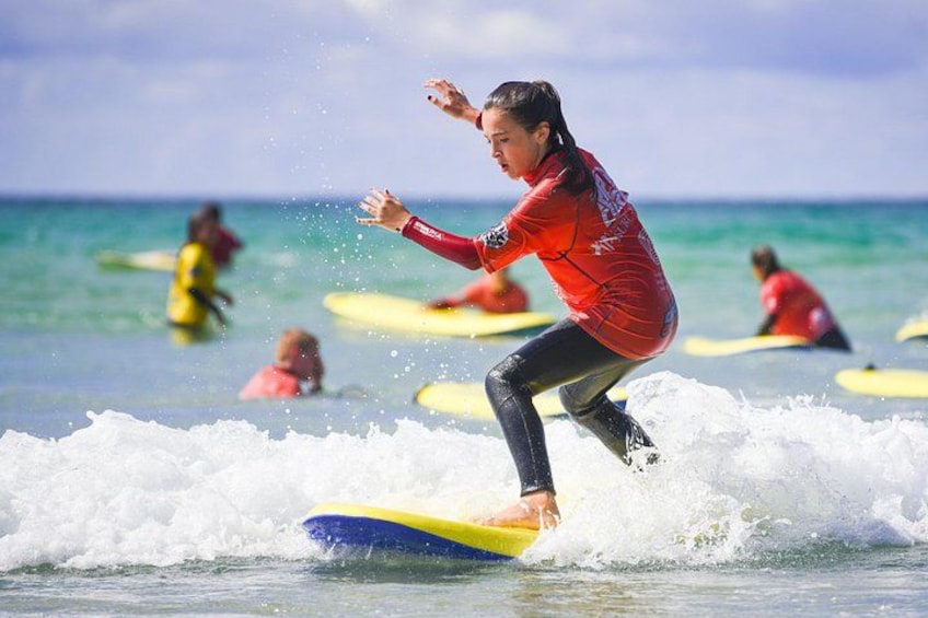 A person surfing on a yellow and blue surfboard. 4