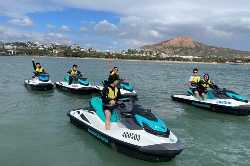 Four people jet-skiing on a body of water with a mountainous landscape in the background. 5