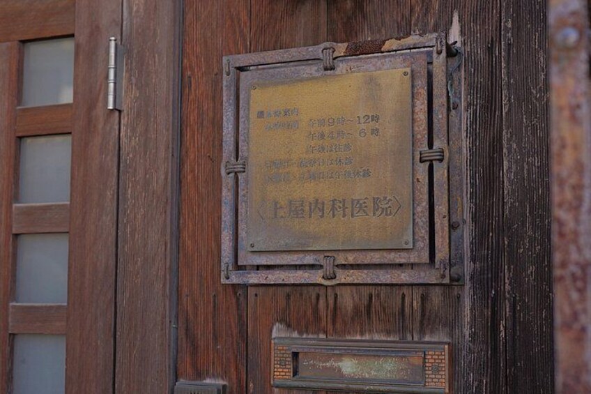 A wooden door with a metal plaque and a smaller plaque below it. 4