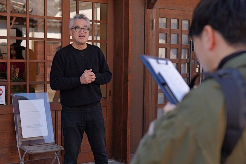 A person standing in front of a wooden door with a glass panel, holding a clipboard. 5