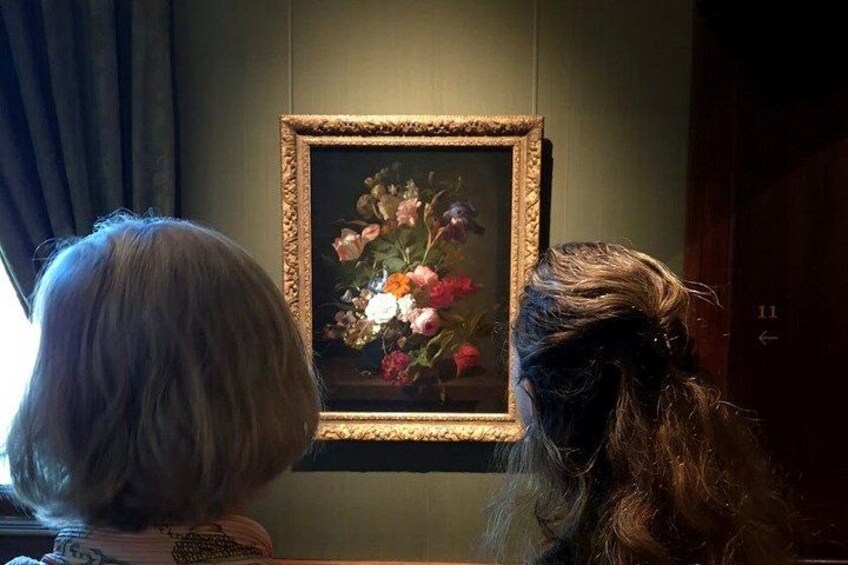 To personer betragter et indrammet blomsterbillede på en væg. 3