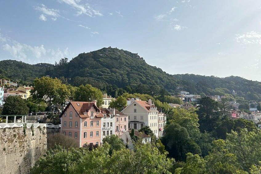 A town with historic buildings, a hill in the background, and a stone wall. 2