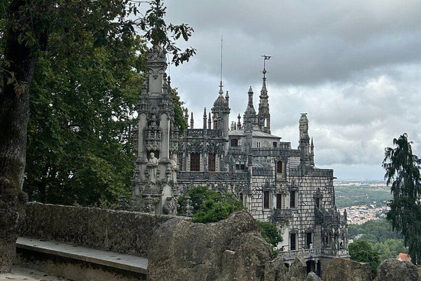 A historic castle with intricate architecture, surrounded by lush greenery and overlooking a distant cityscape. 5