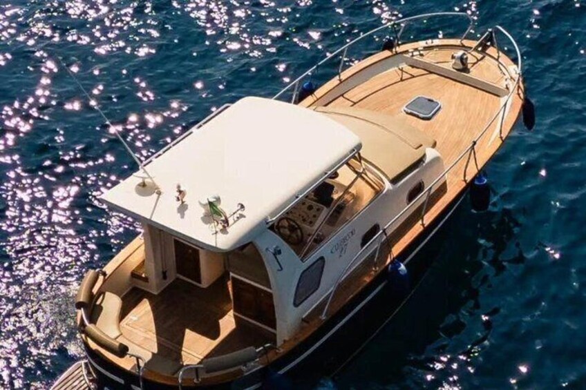 A wooden boat with a cabin and deck chairs on a calm sea. 1