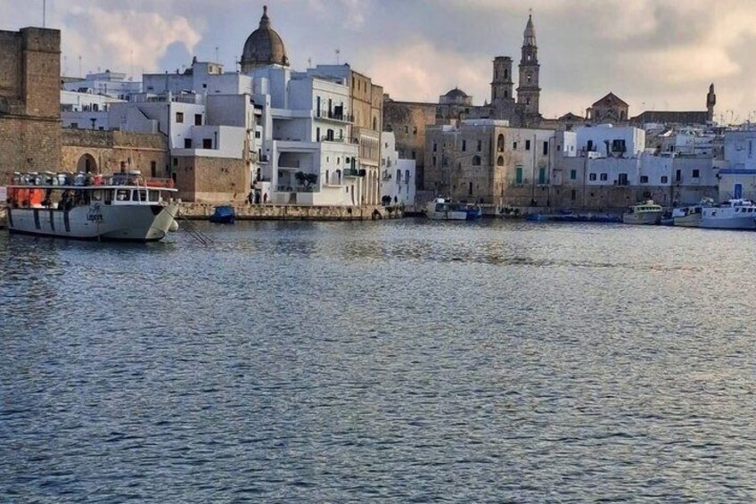 A coastal town with white buildings, a boat docked at the harbor, and a prominent tower in the background. 2