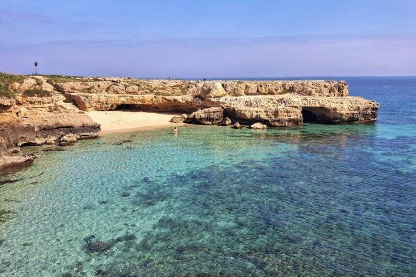 A rocky coastline with clear turquoise water and a sandy beach. 5