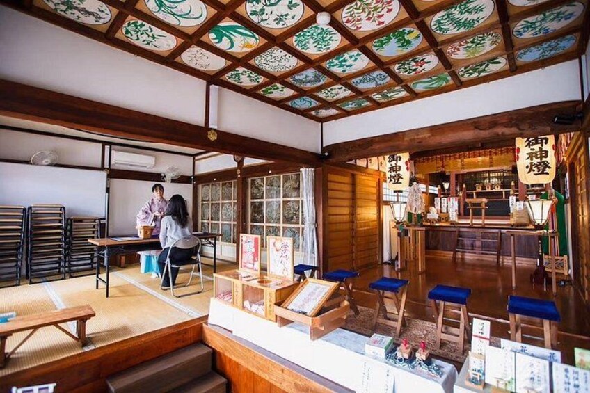 A traditional Japanese interior with tatami mats, a wooden ceiling with decorative panels, and a counter with a sign. 4