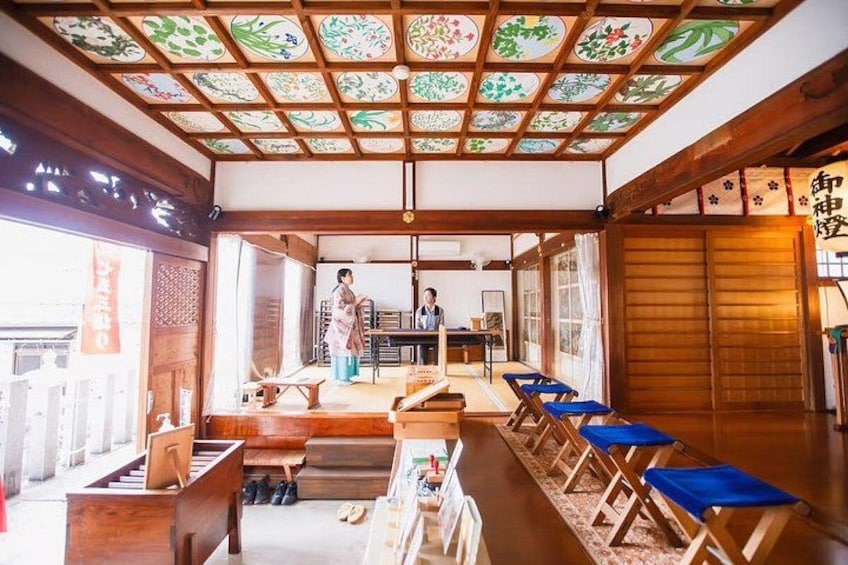 Una habitación japonesa tradicional con esteras de tatami, una mesa baja y una persona de pie junto a la entrada. 5