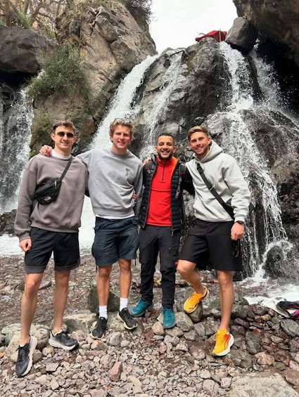 Four people standing in front of a waterfall. 3