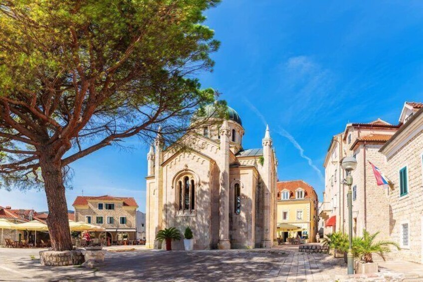 A historic church with a dome, a large tree, and traditional buildings. 2