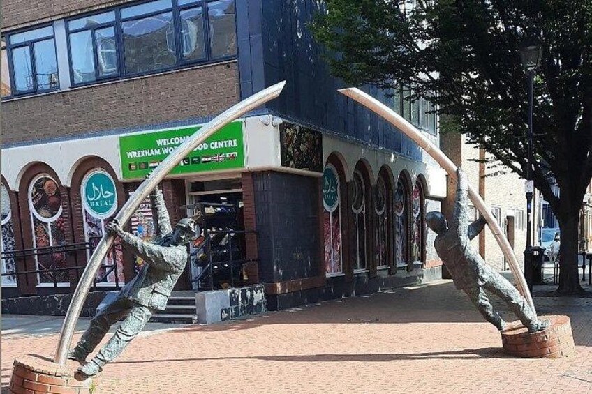 A sculpture of two figures with swords in a public square. 3
