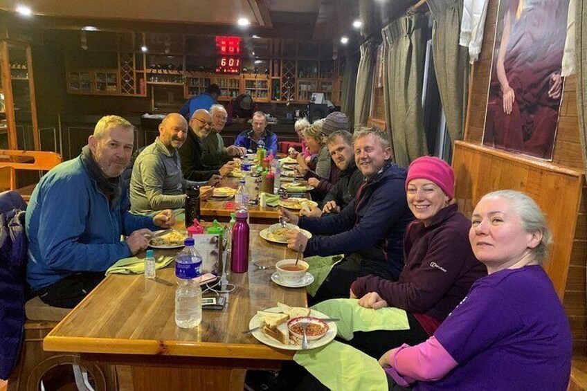 Un groupe de personnes est assis autour d’une table en bois dans un restaurant, et devant elles se trouvent divers plats et boissons. 5