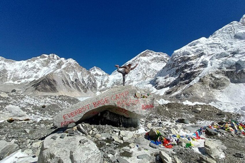 Une personne se tient sur un rocher, à côté d’un panneau indiquant « Camp de base de l’Everest ». 2