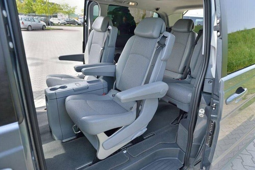 A vehicle interior with two seats, a cup holder, and a door. 3