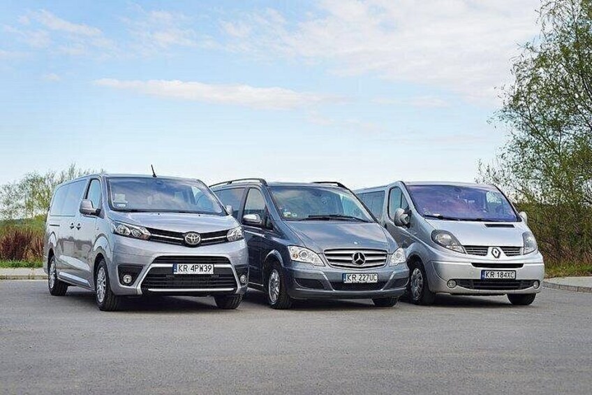 Three cars parked in a row on a paved surface with a clear sky and greenery in the background. 2