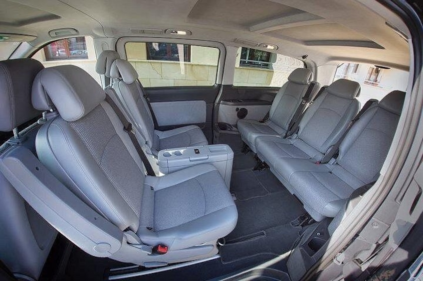 A vehicle interior with grey seats, a central console, and a rearview mirror. 4