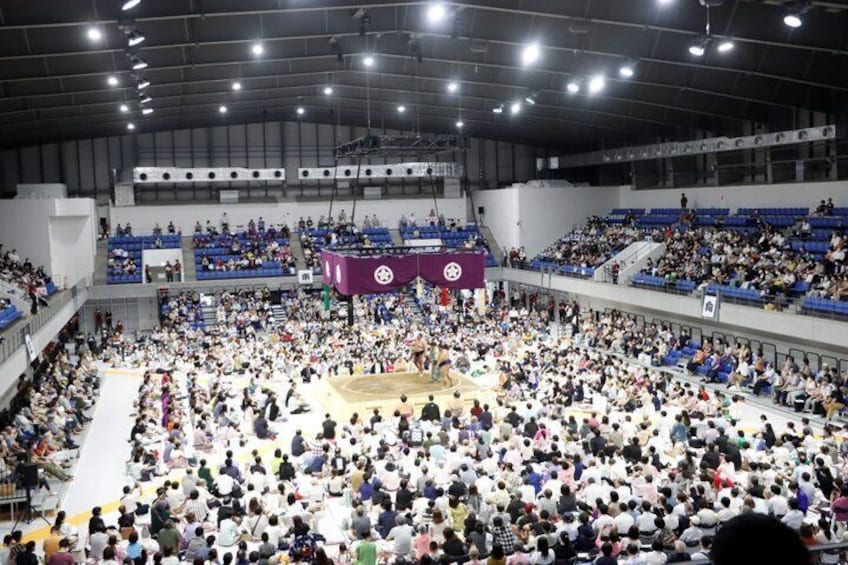 A large indoor arena with a basketball court surrounded by seated spectators. 4