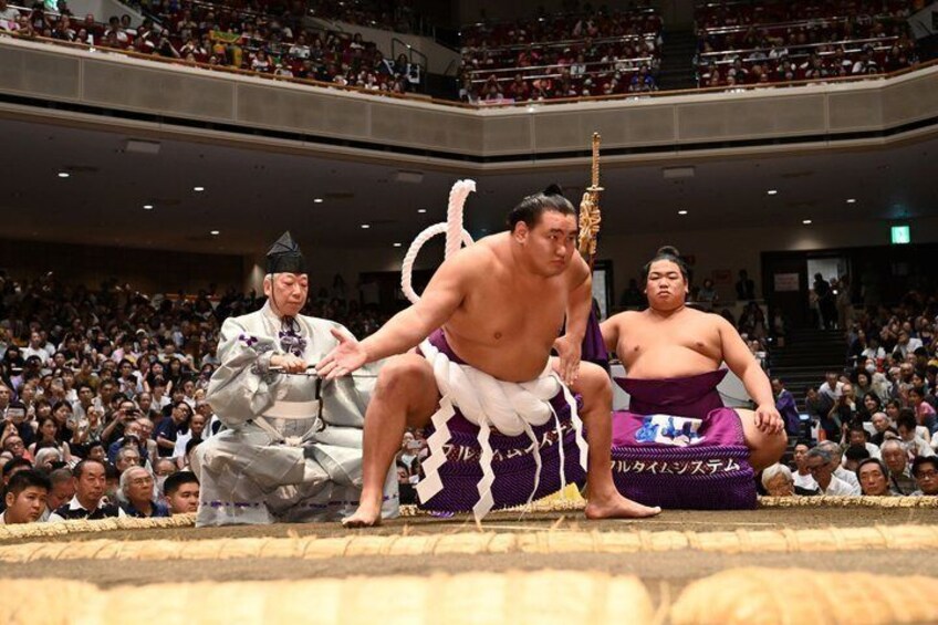 A sumo wrestling match with a large audience in a stadium. 5