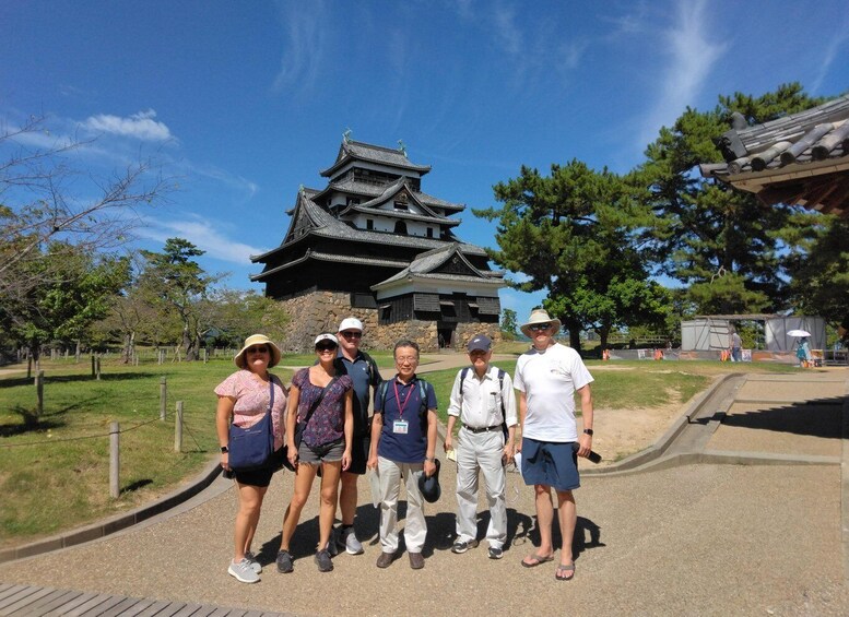 A group of people standing in front of a traditional Japanese building with a tiled roof and wooden structure. 1