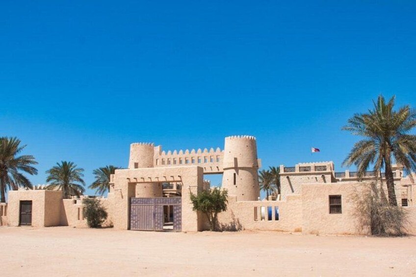 A fortress with a large gate, palm trees, and a clear blue sky. 5