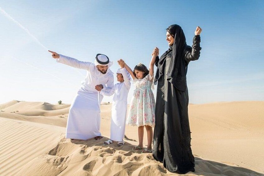 A family in a desert with sand dunes in the background. 3