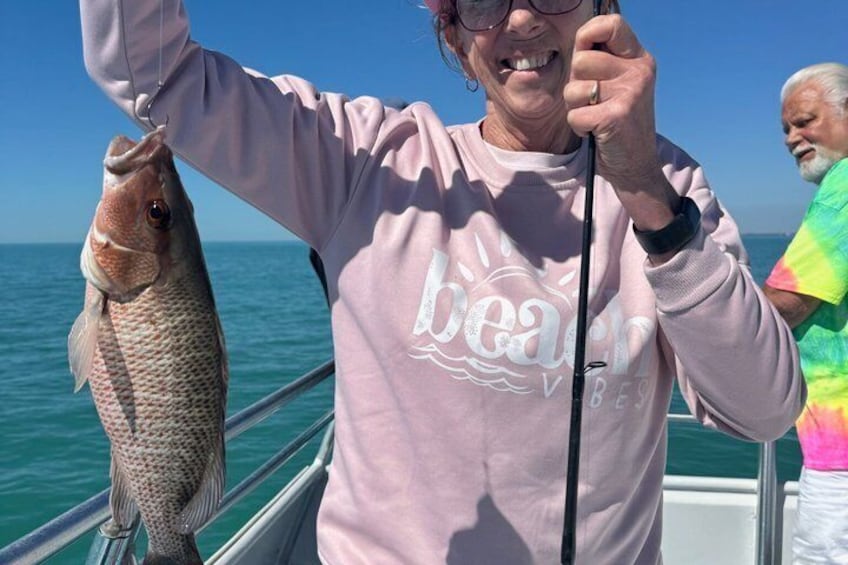A person holding a fish on a boat with the ocean in the background. 3