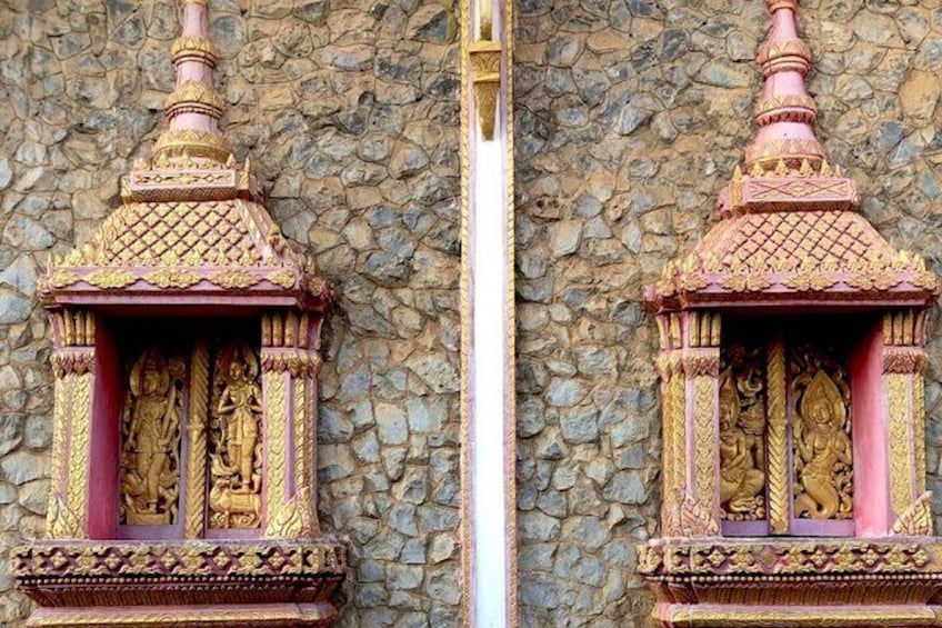 Deux structures de temples richement décorées, aux couleurs or et rose, ornées de sculptures complexes sur un mur de pierre. 5