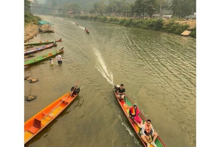 Une rivière avec des bateaux et des canoës, une personne dans un bateau, et un quai avec une structure verte. 4