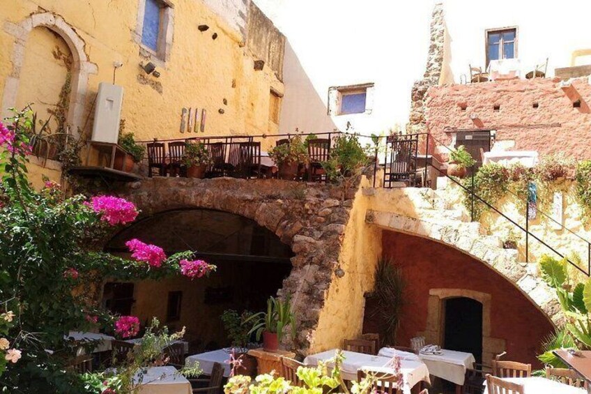 A courtyard with stone archways, outdoor seating, and potted plants. 3