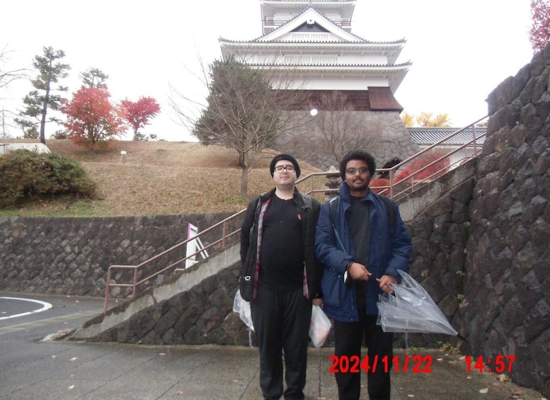 Two individuals standing in front of a traditional Japanese building with a stone staircase. 5