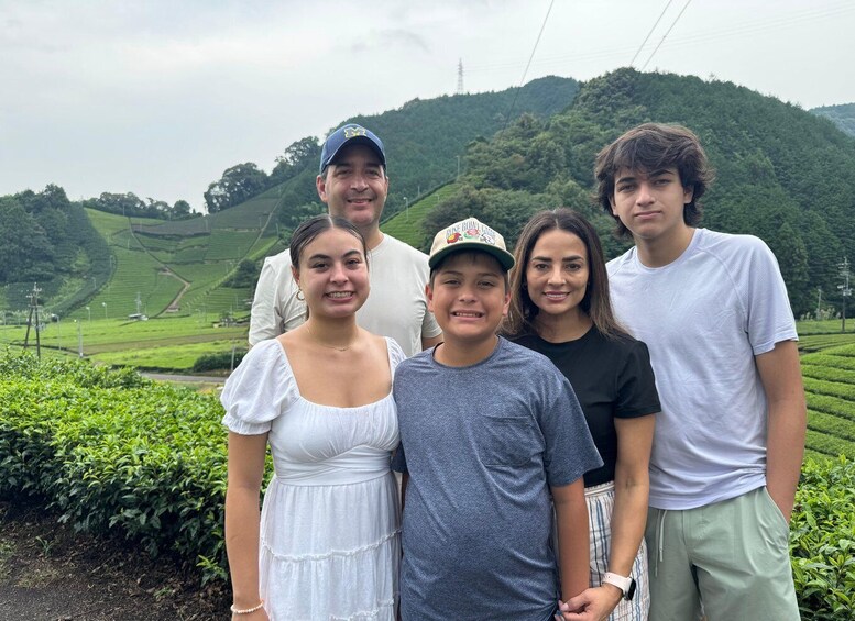 A group of people standing in a hilly landscape with tea plantations. 2