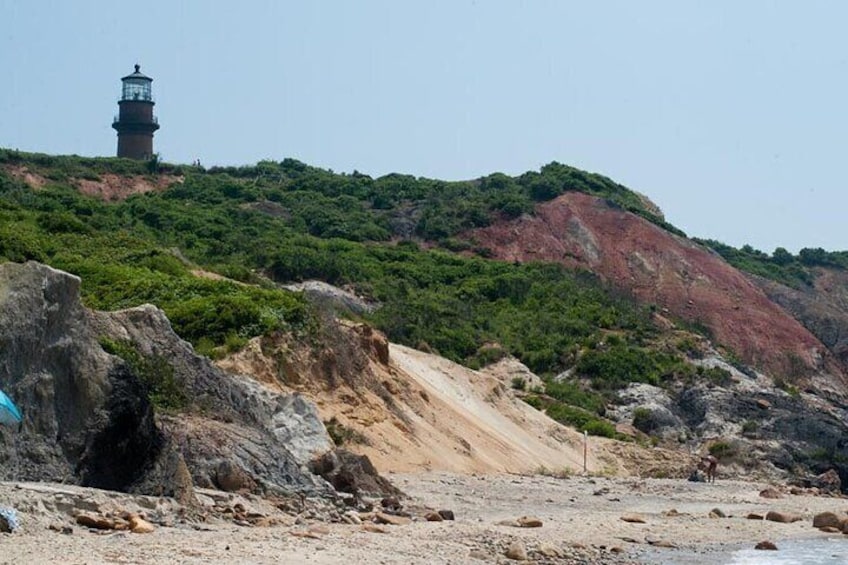 A rocky beach with a lighthouse on a hill. 1