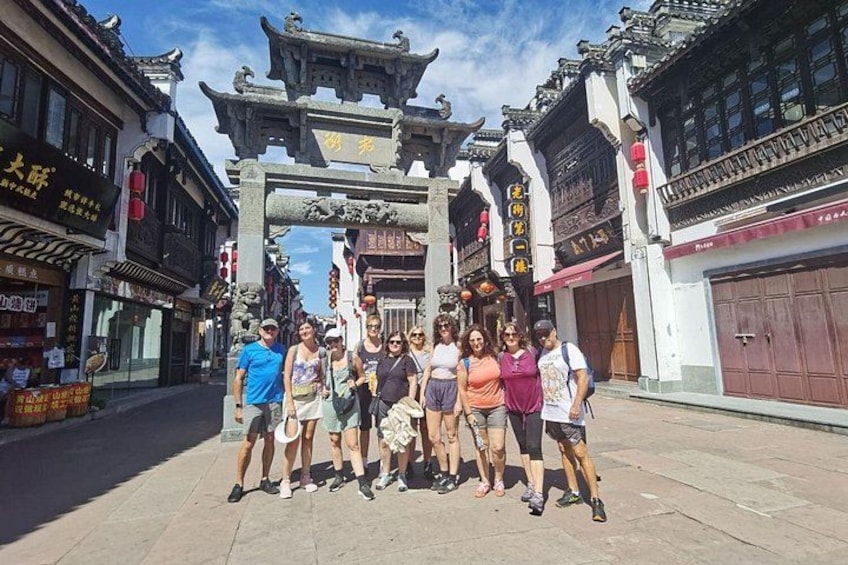 A group of people standing in front of a traditional gate with ornate architecture. 3