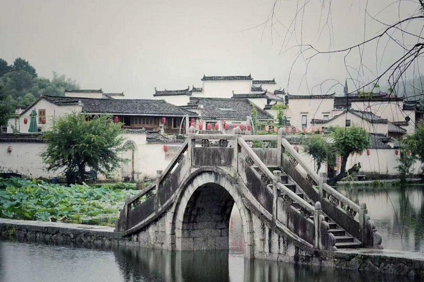 A traditional stone bridge over a calm river, surrounded by historic buildings with tiled roofs. 5