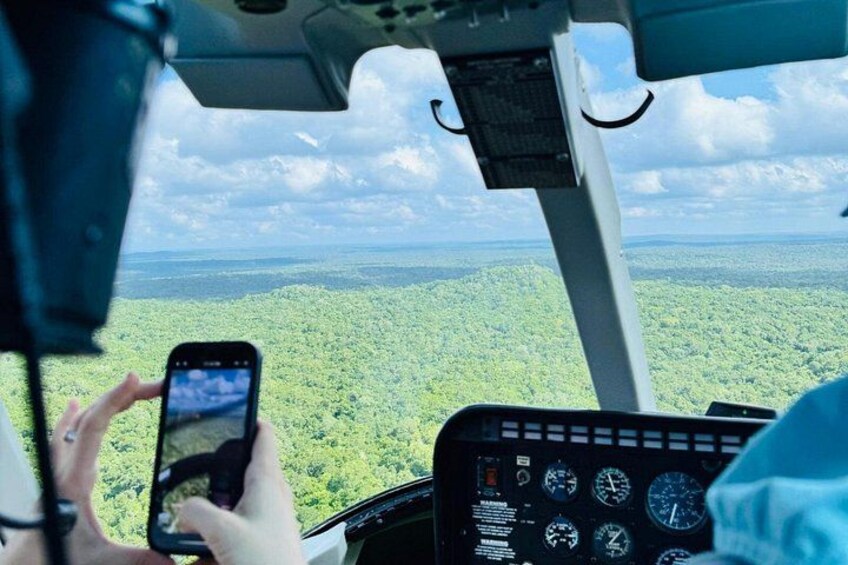 Ein Hubschrauber-Cockpit mit Blick auf einen dichten grünen Wald. 2