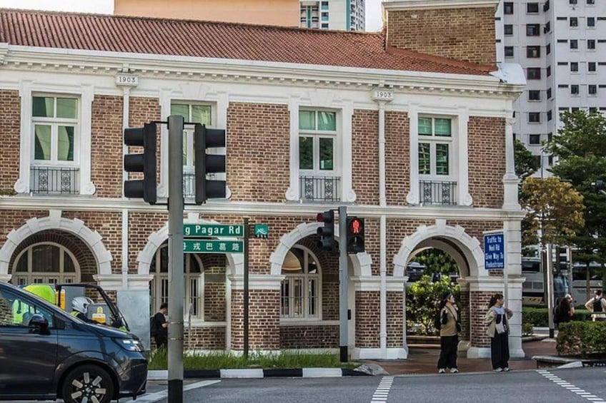 A historic building with brick facade, arched windows, and a street sign for 'Pagar Rd.' 4