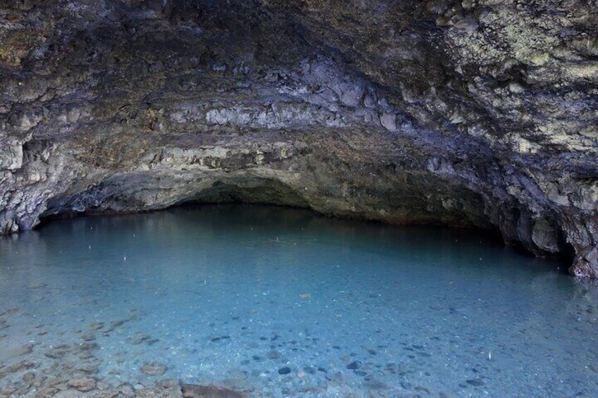 A cave entrance with clear blue water inside. 2
