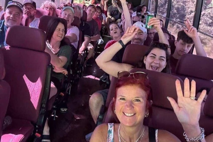 Des personnes sont assises dans un autobus aux grandes fenêtres, et certaines d’entre elles tiennent des boissons à la main. 3