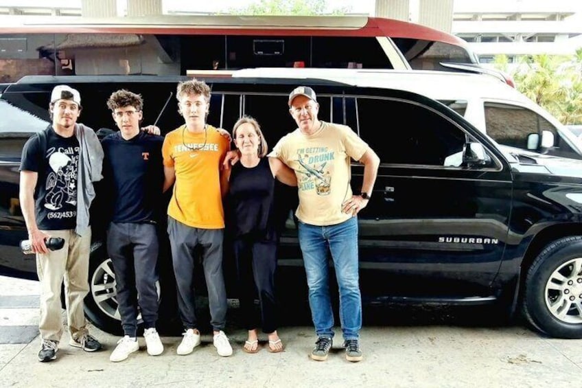 Un groupe de personnes se tient devant un SUV noir dont le toit est rouge. 2