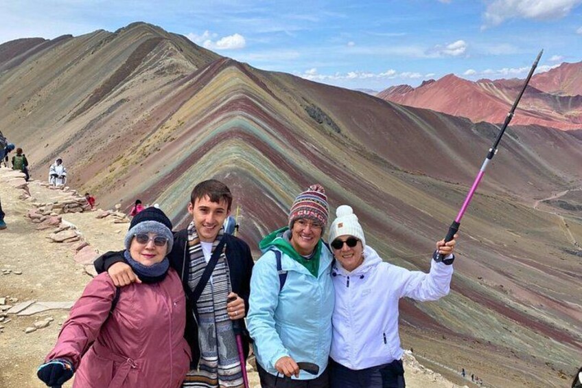 Un groupe de personnes se trouve sur un sentier de montagne, avec des formations rocheuses aux couleurs vives en arrière-plan. 2