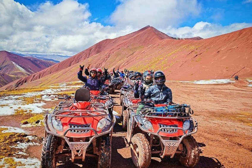 Un groupe de personnes circulant en quads dans une région montagneuse, caractérisée par un sol rouge et une végétation clairsemée. 5