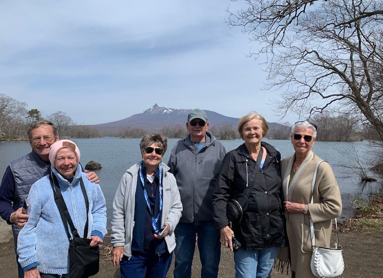 A group of people standing by a lake with a mountain in the background. 4