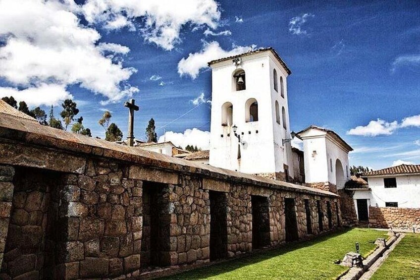 A stone wall, a white building with a bell tower, and a clear blue sky. 4