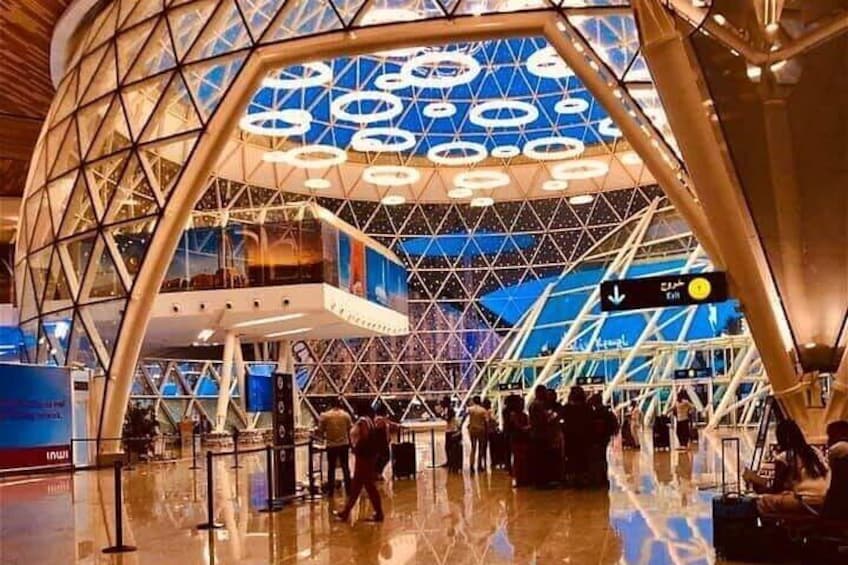 Un terminal d’aéroport moderne doté d’un plafond en verre aux formes géométriques, où l’on voit des gens qui se promènent. 2