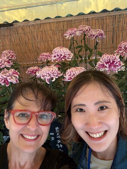 Two people in front of a bamboo fence with pink flowers. 5